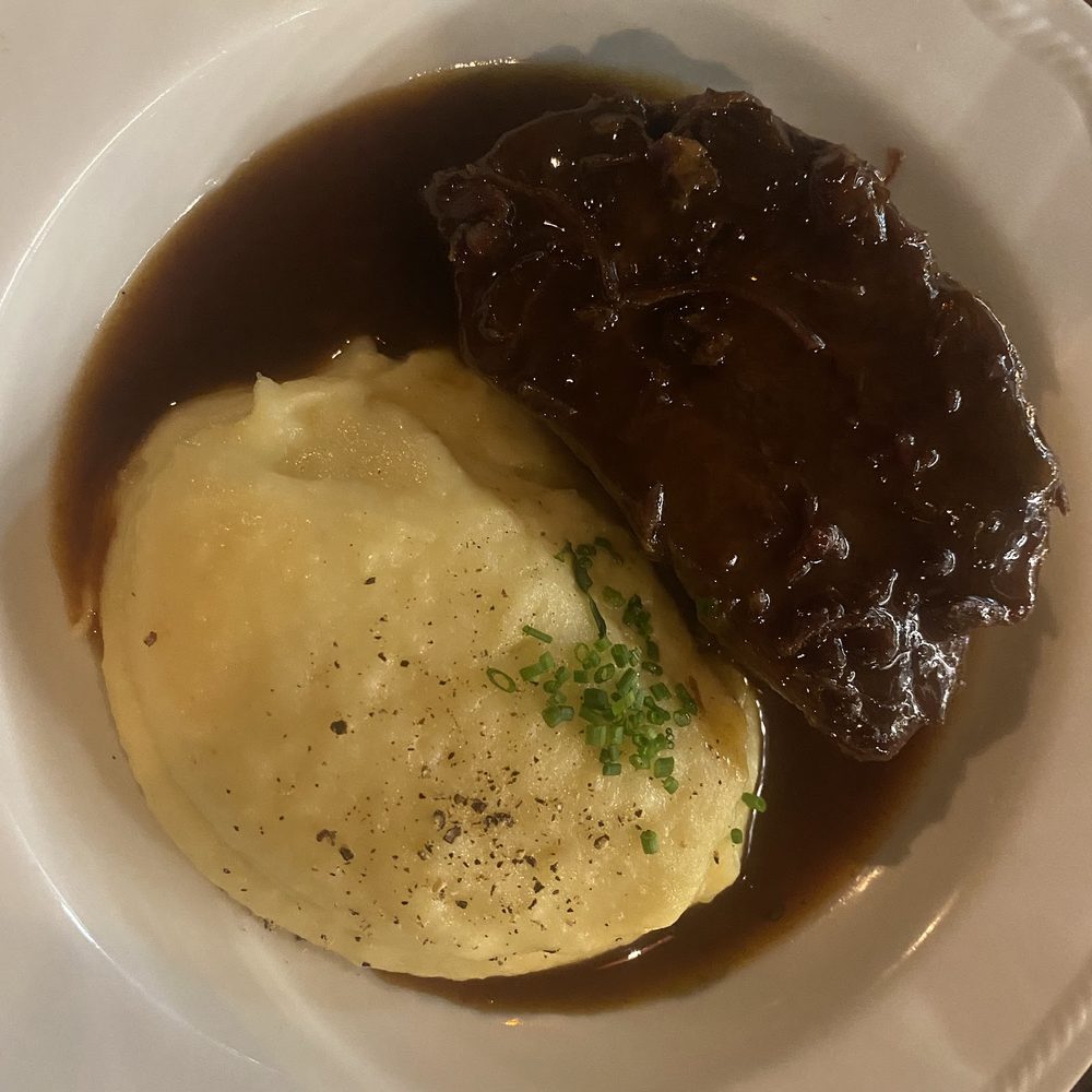 Un secondo di carne brasata nel suo fondo scuro, servito con una quenelle di pur&egrave; e erba cipollina.